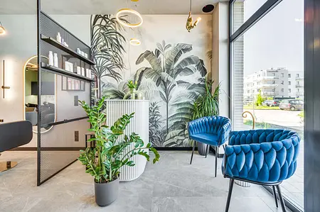 Wnętrze w stylu industrialnym i współczesnym z niebieskimi fotelami i roślinami.
