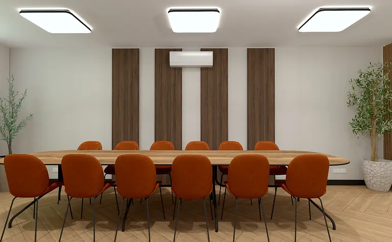 Wnętrze nowoczesnej sali konferencyjnej z drewnianym stołem i pomarańczowymi krzesłami.