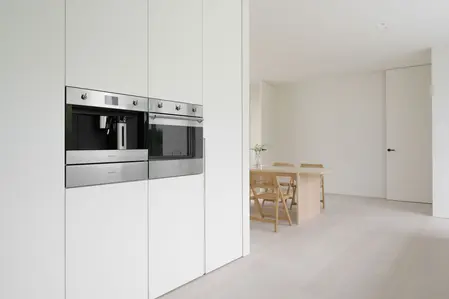 Kuchnia minimalistyczna z białymi meblami i drewnianym stołem w stylu minimaluxe.