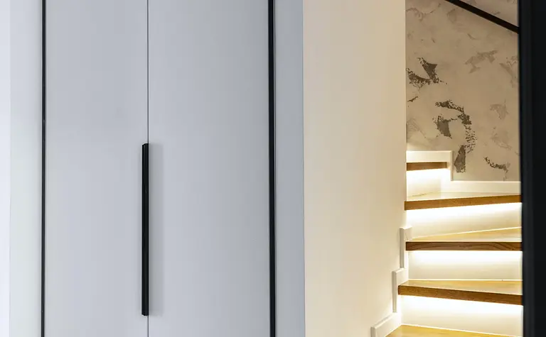 Przestrzeń z białą szafą i drewnianymi schodami, nowoczesny design.