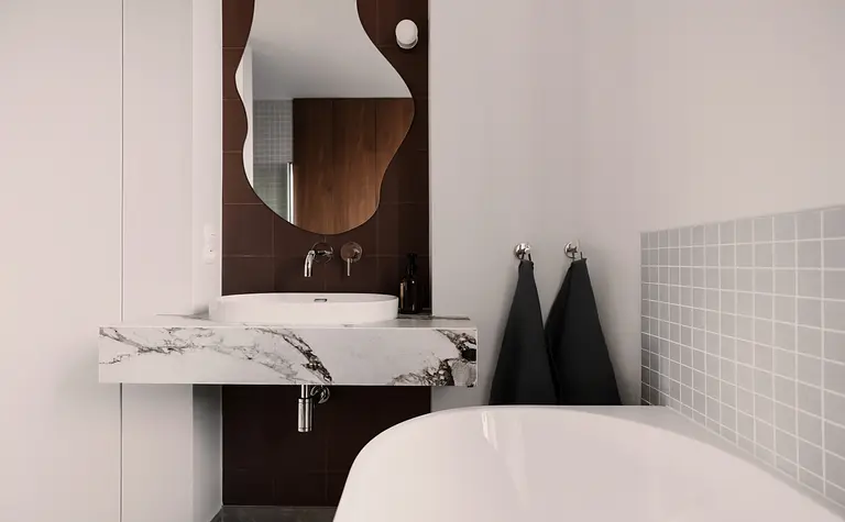 Nowoczesna łazienka z marmurową umywalką, lustrem i szarymi płytkami. Quiet luxury, soft minimalizm, vintage.
