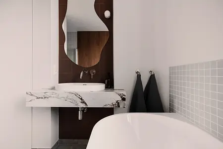 Nowoczesna łazienka z marmurową umywalką, lustrem i szarymi płytkami. Quiet luxury, soft minimalizm, vintage.
