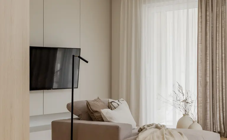 Wnętrze salonu w stylu japandi z minimalistycznym narożnikiem i zasłonami.