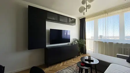 Wnętrze salonu w stylu eklektycznym i minimalistycznym z czarnymi meblami i jasnymi oknami.