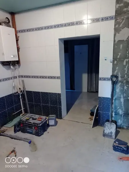 Wnętrze kuchni z białymi płytkami, niebieskimi akcentami i narzędziami budowlanymi.