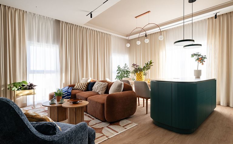 Wnętrze współczesnego salonu z brązową sofą i zieloną wyspą kuchenną.