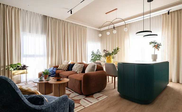 Wnętrze współczesnego salonu z brązową sofą i zieloną wyspą kuchenną.