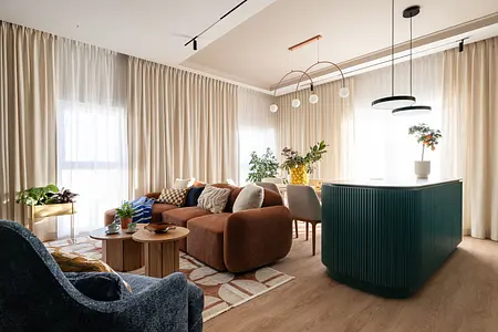 Wnętrze współczesnego salonu z brązową sofą i zieloną wyspą kuchenną.