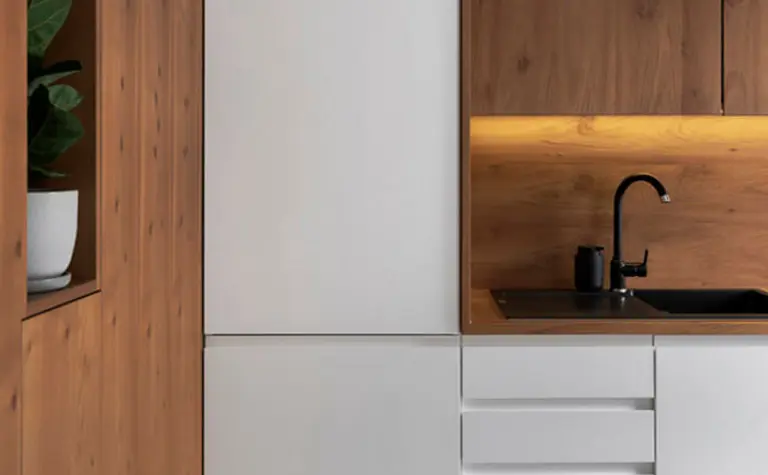 Nowoczesna kuchnia z białymi szafkami i drewnianym wykończeniem, minimalistyczny design.