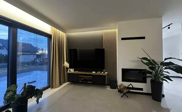 Wnętrze salonu z telewizorem, roślinami i nowoczesnym kominkiem, styl industrialny