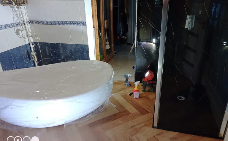 Wnętrze łazienki z białą wanną i czarnym prysznicem w stylu glamour.