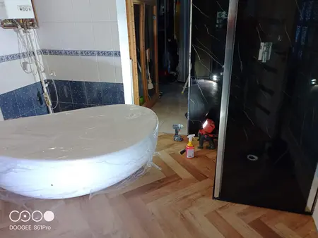 Wnętrze łazienki z białą wanną i czarnym prysznicem w stylu glamour.