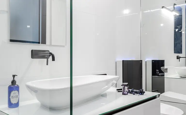 Nowoczesna łazienka z białą umywalką i czarnymi detalami, minimalistyczny design.