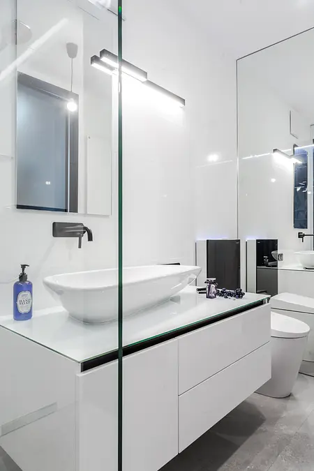 Nowoczesna łazienka z białą umywalką i czarnymi detalami, minimalistyczny design.
