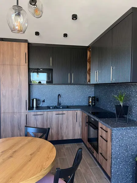 Nowoczesna kuchnia w stylu quiet luxury z drewnem i czarnymi detalami.