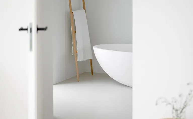 Minimalistyczna łazienka z białą wanną i drewnianymi detalami, styl minimaluxe.