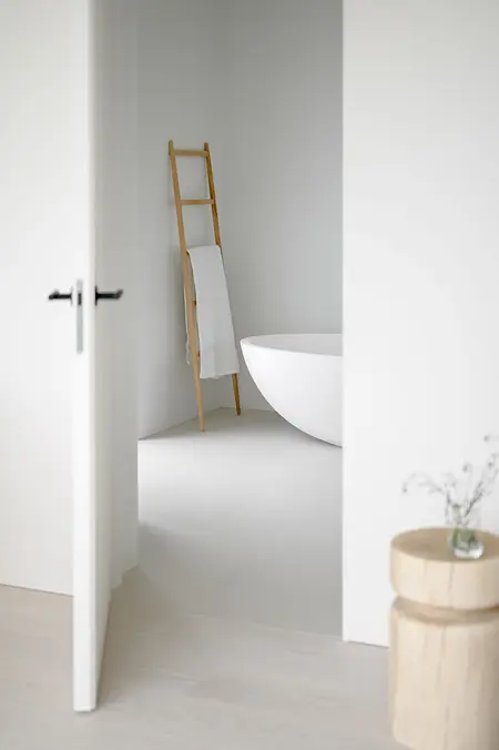 Minimalistyczna łazienka z białą wanną i drewnianymi detalami, styl minimaluxe.
