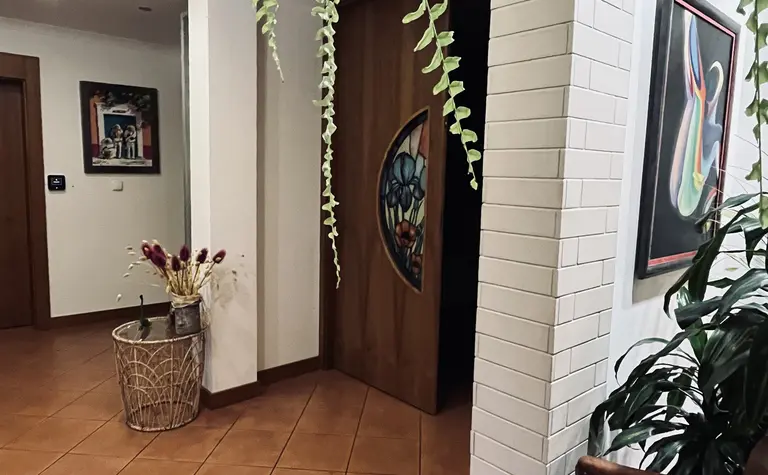 Przedpokój z drewnianymi drzwiami, roślinami i obrazami w stylu vintage.