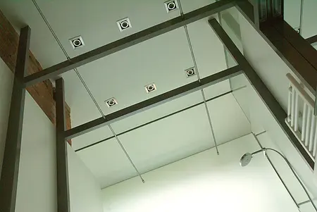 Eklektyczne wnętrze z industrialnym sufitem i nowoczesnym oświetleniem.