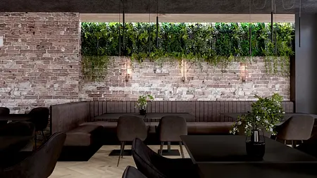Restauracja z ceglaną ścianą, ciemnymi meblami i roślinnością, styl industrialny.
