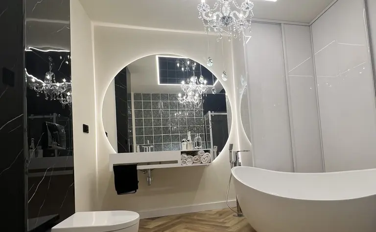 Luksusowa łazienka z wanną, lustrem i kryształowym żyrandolem w stylu glamour.