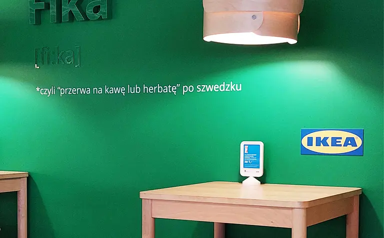 Wnętrze kawiarni ze zieloną ścianą i drewnianymi meblami, styl skandynawski.