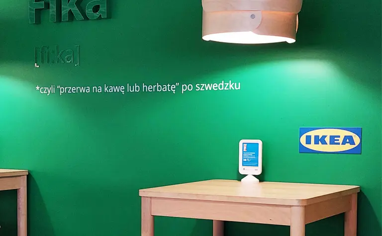 Wnętrze kawiarni ze zieloną ścianą i drewnianymi meblami, styl skandynawski.