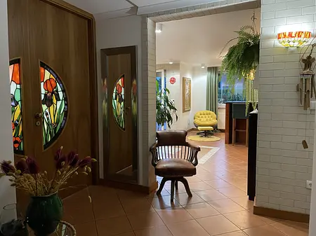 Przedpokój w stylu vintage z witrażowymi drzwiami i żółtym fotelem.