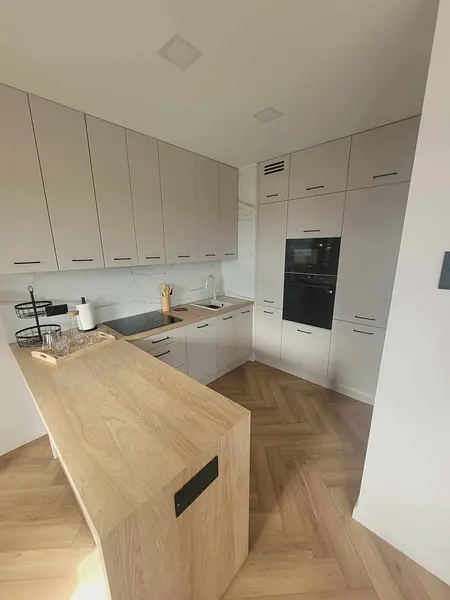 Nowoczesna kuchnia z szarymi meblami i drewnianą wyspą, idealna do gotowania.