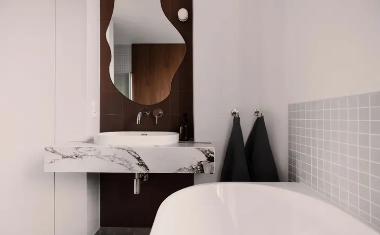 Nowoczesna łazienka z marmurową umywalką, lustrem i szarymi płytkami. Quiet luxury, soft minimalizm, vintage.