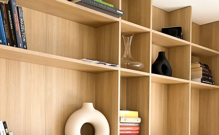 Minimalistyczne wnętrze z półkami, książkami i dekoracjami w stylu soft minimalizm.
