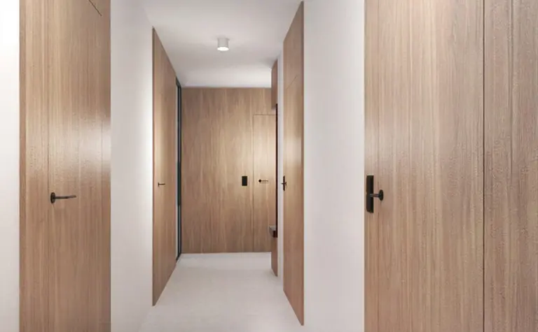 Korytarz z minimalistycznym designem, drewniane drzwi i jasne ściany