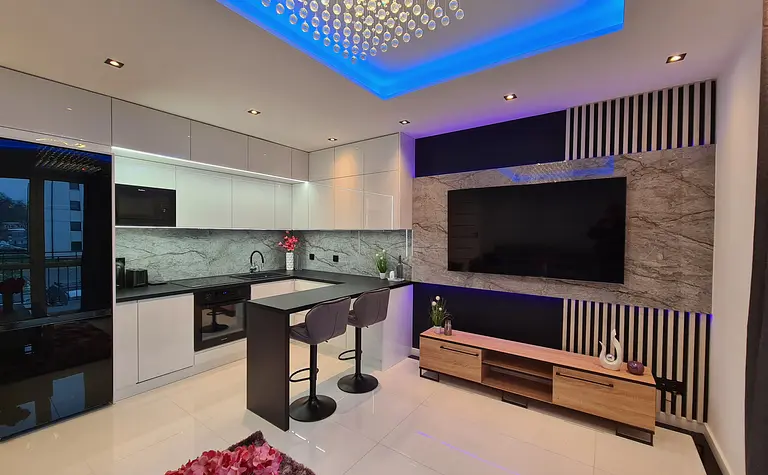 Nowoczesna kuchnia z białymi meblami i czarnymi detalami, z eleganckim blatem.