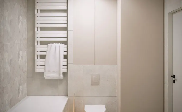 Nowoczesna łazienka z wanną, białym grzejnikiem i minimalistycznymi meblami.