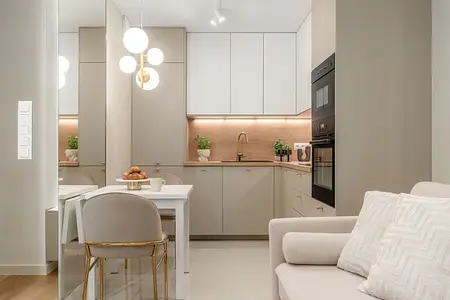 Wnętrze kuchni z szarymi meblami, białym blatem i drewnianymi akcentami