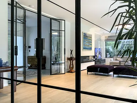 Wnętrze salonu minimalistycznego z dużymi oknami, drewnianą podłogą i roślinnością. Styl minimaluxe, quiet luxury.