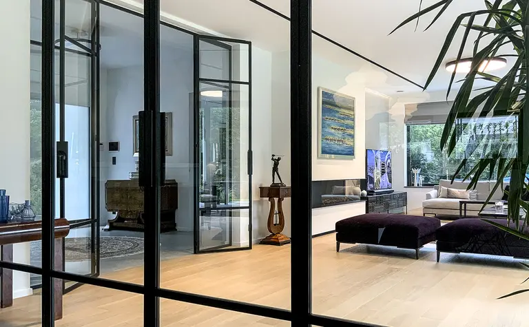 Wnętrze salonu minimalistycznego z dużymi oknami, drewnianą podłogą i roślinnością. Styl minimaluxe, quiet luxury.
