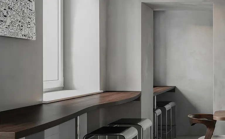 Wnętrze kuchni w stylu industrialnym z minimalistycznym drewnianym blatem i szarymi ścianami.