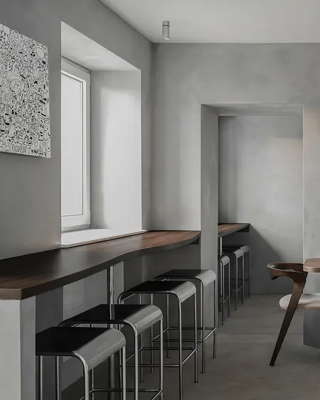 Wnętrze kuchni w stylu industrialnym z minimalistycznym drewnianym blatem i szarymi ścianami.