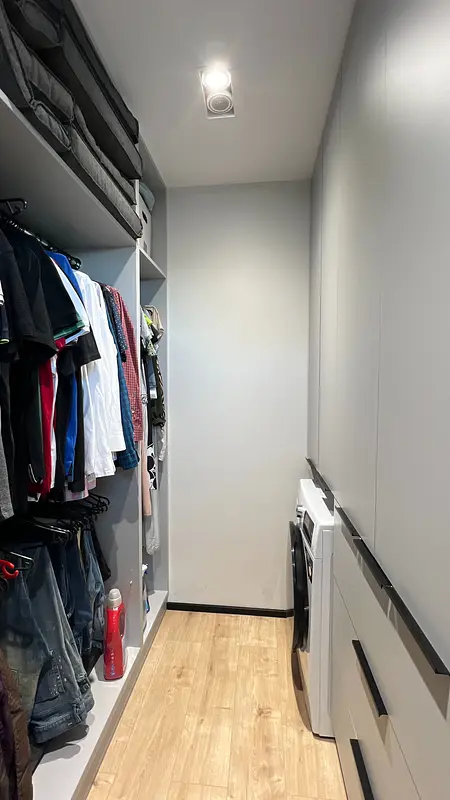 Garderoba w stylu nowoczesnym i soft minimalizm, z szarymi szafkami i drewnianą podłogą.