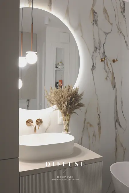 Nowoczesna łazienka z okrągłym lustrem, minimalistycznym designem i akcentami boho.