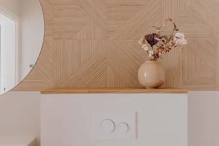 Wnętrze łazienki z drewnianą ścianą i wazonem w stylu skandynawskim.