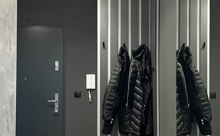 Nowoczesny przedpokój w soft minimalizmie z szarymi ścianami i lustrami.