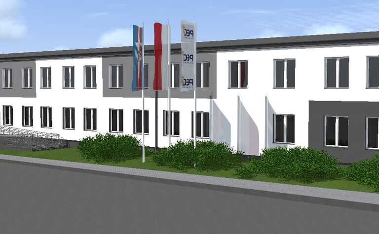 Widok budynku z szaro-białą elewacją i zielonymi krzewami, styl industrialny i nowoczesny.