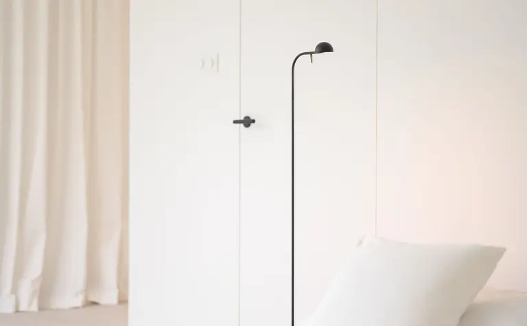 Minimalistyczna sypialnia z białymi meblami i czarną lampą, styl minimaluxe.