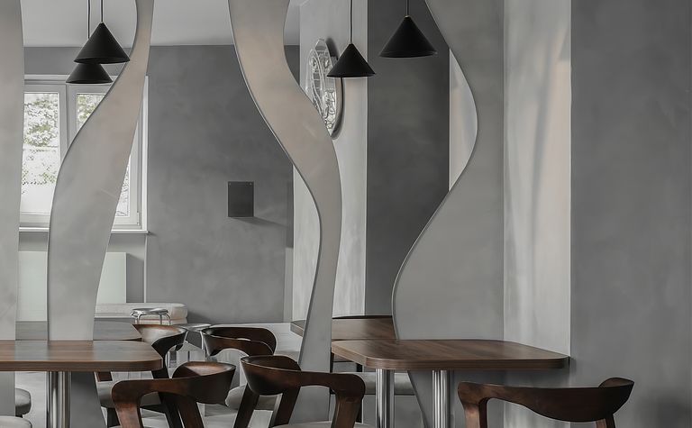 Wnętrze jadalni w stylu industrialnym i minimalistycznym z drewnianym stołem i szarymi ścianami.