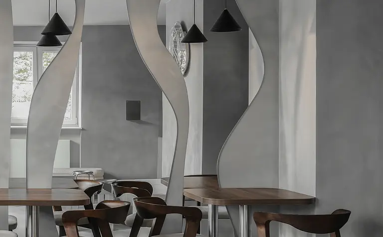 Wnętrze jadalni w stylu industrialnym i minimalistycznym z drewnianym stołem i szarymi ścianami.