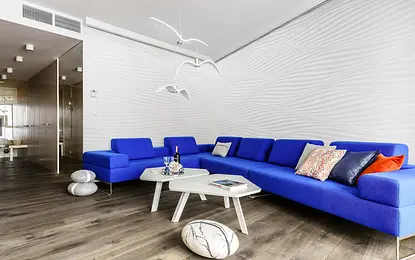 Wnętrze salonu w stylu skandynawskim z niebieską sofą i białym stolikiem.