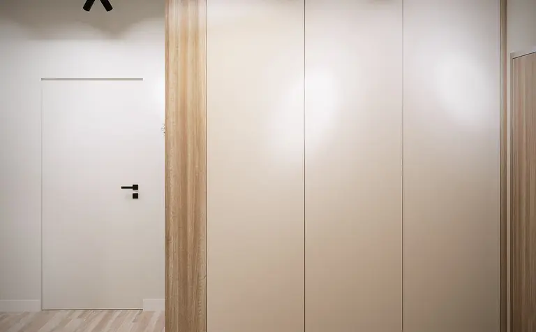 Przedpokój w minimalistycznym stylu z jasnymi szafkami i drewnianą podłogą.