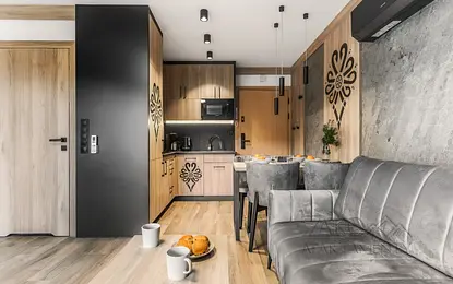 Wnętrze kuchni z drewnianymi meblami, szarym stołem i dekoracjami.